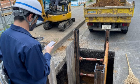 A worker reports construction status at the site using a smartphone